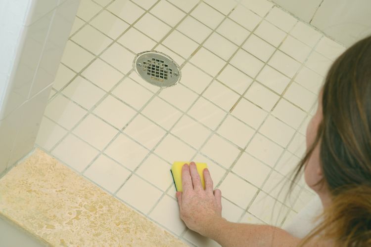 scrubbing black mold on shower floor